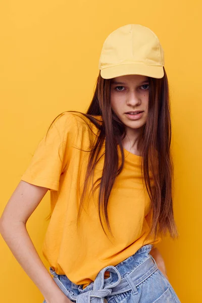 Φωτογραφία όμορφη γυναίκα ποζάρουν σε ένα κίτρινο T-shirt και καπάκι απομονωμένο φόντο — Φωτογραφία Αρχείου