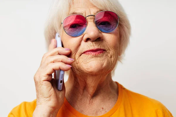 Улыбающаяся пожилая женщина в повседневных футболках в солнцезащитных очках разговаривает по телефону эмоции крупным планом — стоковое фото