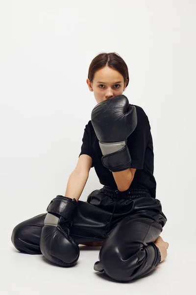 Mujer joven en guantes de boxeo en el suelo en camiseta negra fondo aislado —  Fotos de Stock