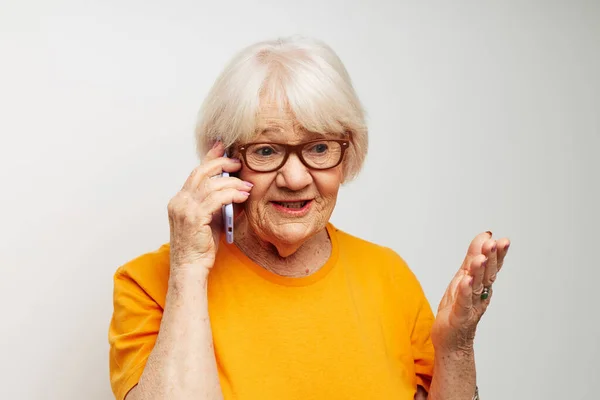 Mujer de edad avanzada en gafas de sol casuales camiseta hablando en el fondo de luz del teléfono — Foto de Stock