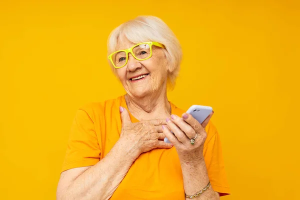 Foto de la vieja señora jubilada divertido hablando en el fondo amarillo del teléfono — Foto de Stock