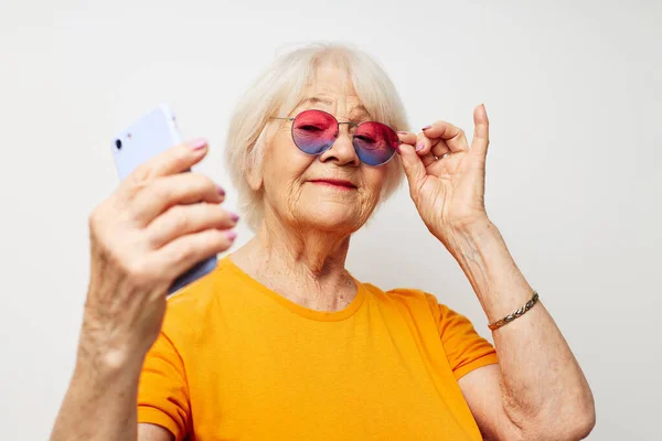 手でスマートフォンでファッショナブルなメガネで引退した老婦人の写真クロップドビュー — ストック写真
