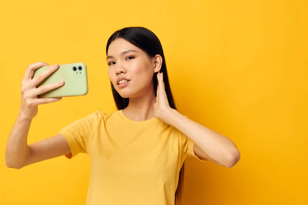 스마트폰을 손에 들고 아시아의 모습을 하고 있는 한 여성 이 변경되지 않은 감정을 가까운 스튜디오 모델로 삼고 있다. — 스톡 사진