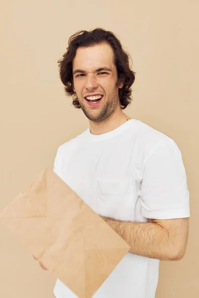 Vrolijke man papier kruidenierszakje poseren geïsoleerde achtergrond — Stockfoto