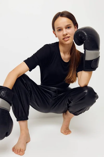 Foto bonita chica en pantalones negros en el suelo guantes de boxeo fondo claro — Foto de Stock