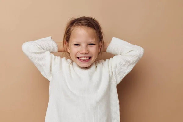 Портрет счастливой улыбающейся девочки в белом свитере, изображающей жесты рук — стоковое фото