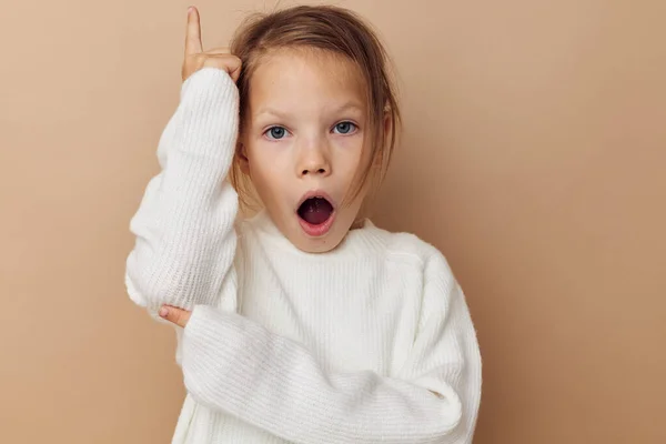 Маленькая девочка в белом свитере позирует рукой жесты детства неизменными — стоковое фото