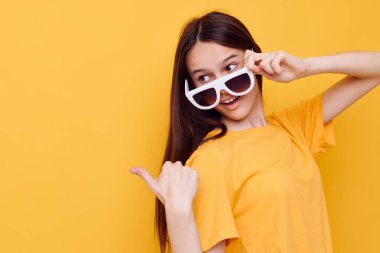 Uzun saçlı, güneş gözlüğü takan, izole edilmiş arka plan pozu veren güzel bir kız.