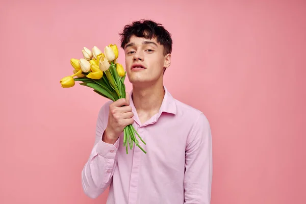 Красивий хлопець в рожевій сорочці з букетом квітів жестикулює руками ізольований фон незмінний — стокове фото