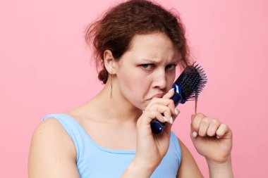 Güzel bir kadın saçlarını taramaktan hoşlanmaz pembe arka plan değişmez