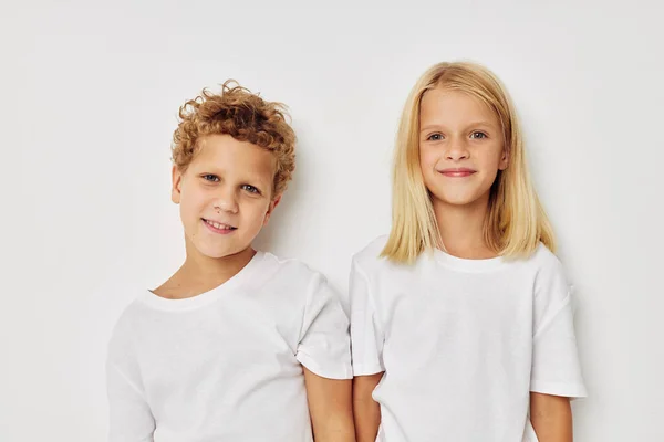 Foto de duas crianças em camisetas brancas estão de pé ao lado do fundo bege — Fotografia de Stock