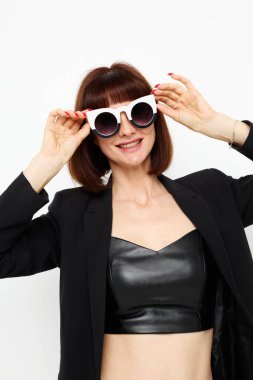 Siyah ceketli bir kadının portresi kırmızı ojeli, şık güneş gözlüklü, izole bir arka plan.