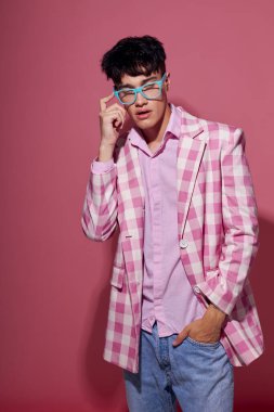 Moda gözlüklü genç bir adam. Pembe ceket. Stüdyo pembe arka plan değiştirilmemiş.