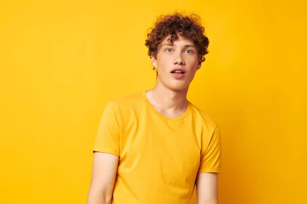 Fiatal göndör hajú férfi elegáns sárga pólóban pózol Életmód változatlan — Stock Fotó
