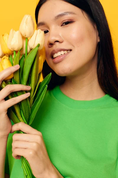 Гарна брюнетка зелена футболка букет жовтих квітів ізольований фон незмінний — стокове фото