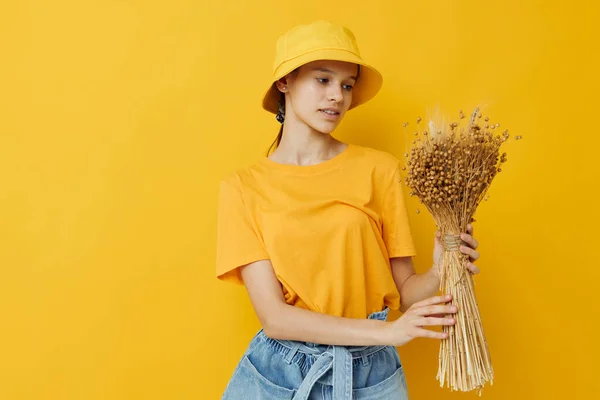 Joven hermosa mujer un ramo de flores secas en las manos estilo juvenil casual desgaste amarillo fondo —  Fotos de Stock