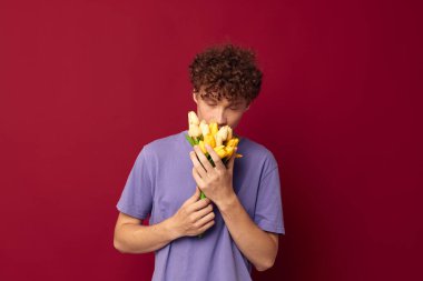 Hoş kızıl saçlı, sıradan bir çiçek buketi takıyor. Kırmızı arka plan değişmemiş.