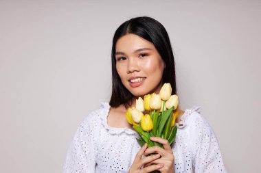 Asyalı bir buket çiçekle güzel bir genç kadın portresi. Arka planda hiç değişmeden gülümse.