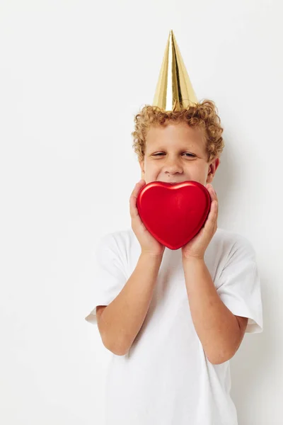 Vidám fiú sapkával a fején egy ajándékdoboz szív formájában. — Stock Fotó