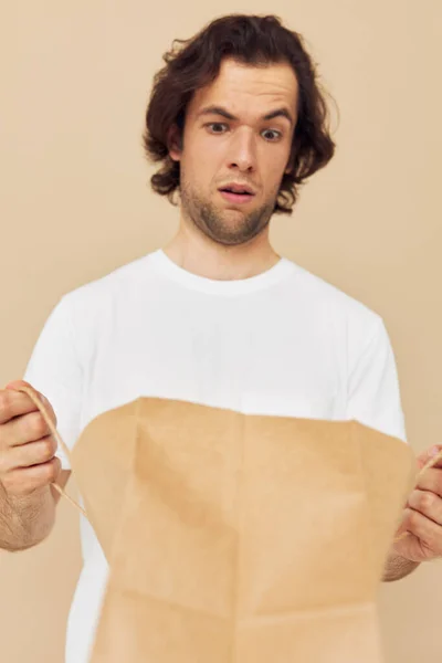 Homem bonito em uma camiseta branca com saco de papel Estilo de vida inalterado — Fotografia de Stock