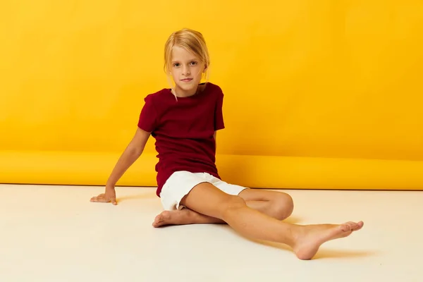 Yerde oturan kız sarı arka plan pozu veriyor. — Stok fotoğraf