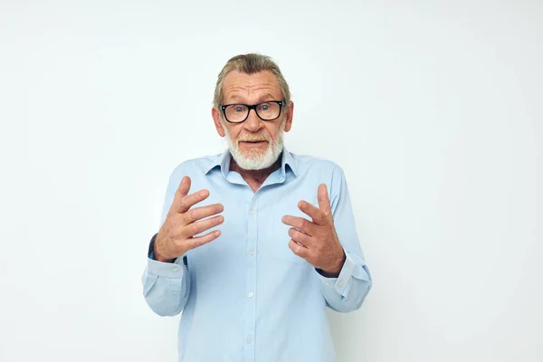 Starší šedovlasý muž v modrých košilích gesta s rukama světlé pozadí — Stock fotografie