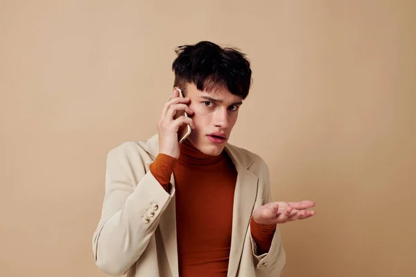 若い男のポーズで携帯電話で彼の手にジャケットエレガントなスタイルのモデルスタジオ — ストック写真