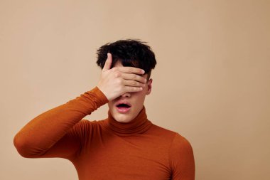 Genç bir adam stil sahibi kahverengi balıkçı yaka kazak değiştirilmemiş bir arka plan.