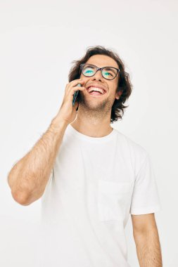 Beyaz tişörtlü çekici bir adam telefonla iletişim kuruyor.