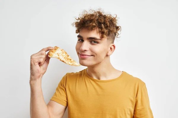 Красивий хлопець в жовтій футболці, що їсть піцу ізольований фон — стокове фото