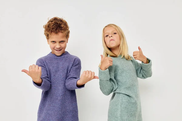 Fotografie dvou dětí v pestrobarevných svetrech pózujících pro zábavu dětství v nezměněném stavu — Stock fotografie