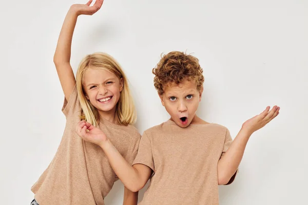 Bonito crianças elegantes em camisetas bege posando para a infância divertida inalterada — Fotografia de Stock
