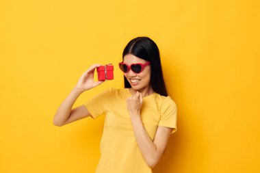 Çekici genç Asyalı kadın moda gözlükleri hediye sarı arka plan değiştirilmemiş
