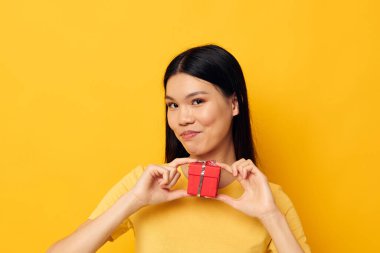 Güzel esmer, elinde bir hediye kutusu var. Arka planda bir değişiklik olmamış gibi duruyor.