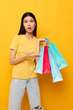 Sarı tişörtlü güzel esmer, çok renkli alışveriş çantalı stüdyo modeli değiştirilmemiş.