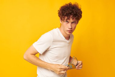 Beyaz tişörtlü, kırmızı kıvırcık saçlı mavi gözlükleri olan bir adam.