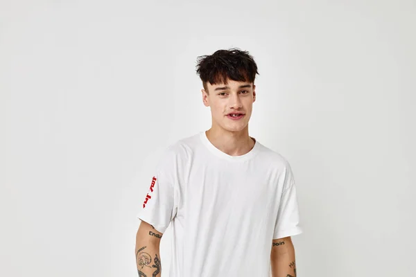 Молодий чоловік татуювання на руках у білій футболці світлий фон незмінний — стокове фото