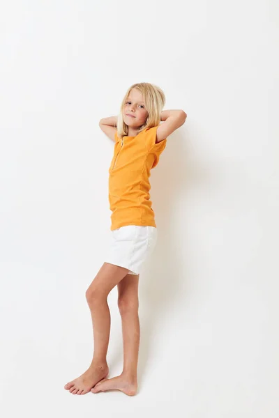 Kleines Mädchen mit blonden Haaren voller Wachstum barfuß auf hellem Hintergrund — Stockfoto