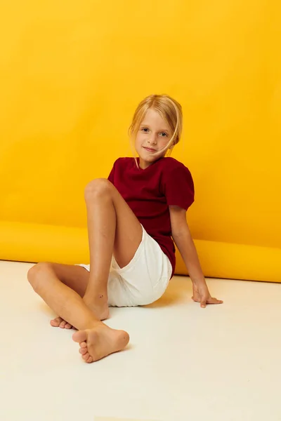 Fröhliches Mädchen mit blonden Haaren gestikuliert mit ihren Händen gelben Hintergrund — Stockfoto