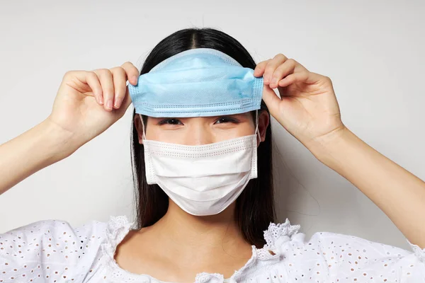 Charming young Asian woman medical mask protection light background unaltered — 图库照片