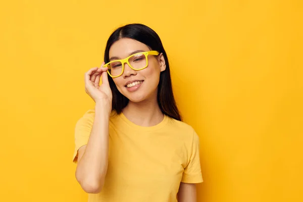 Morena bonita em óculos gesticulando com as mãos copia-espaço amarelo fundo inalterado — Fotografia de Stock