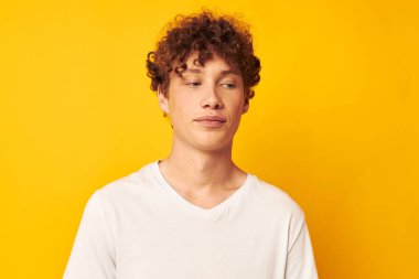 Sarı arka planda beyaz tişörtlü, kıvırcık kızıl saçlı adam.