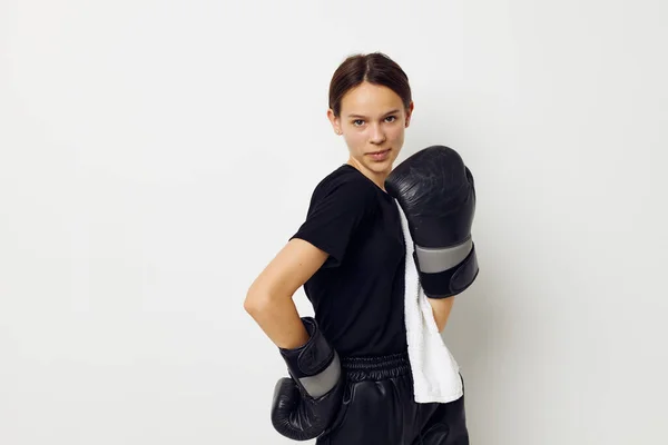 Atletisk kvinna i boxningshandskar i svarta byxor och en T-shirt isolerad bakgrund — Stockfoto