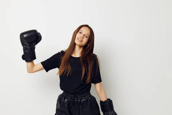 Mujer atlética en negro deportes uniforme guantes de boxeo posando fondo aislado —  Fotos de Stock