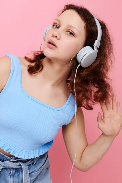Портрет милой молодой девушки в наушниках, слушающей музыку розового фона без изменений — стоковое фото