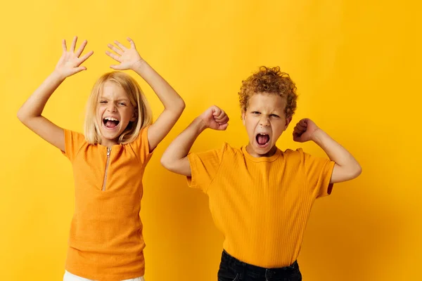 Leuke stijlvolle kinderen casual slijtage spelletjes leuk samen poseren op gekleurde achtergrond — Stockfoto