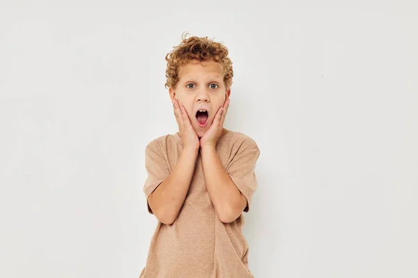 Vrolijke jongen in beige T-shirt emoties poseren lichte achtergrond — Stockfoto