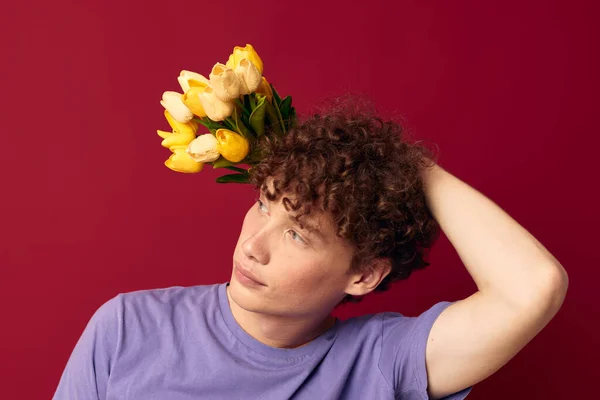 Adolescente sosteniendo un ramo amarillo de flores púrpura camisetas aislado fondo inalterado — Foto de Stock