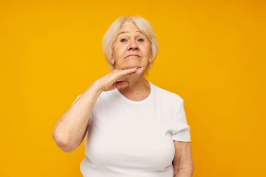 Beyaz tişörtlü yaşlı bir kadın izole edilmiş eğlenceli bir arka plan oluşturuyor.