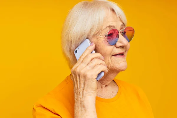 スマートフォンの隔離された背景を持つファッショナブルなメガネで引退した老婦人の写真 — ストック写真